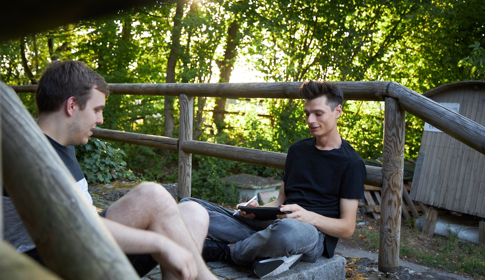 Im Grünen sitzen Julius und Emanuel und arbeitet an einem Laptop